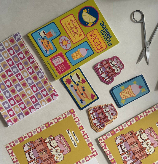 Colorful journalling supplies and stickers on a white surface with scissors.