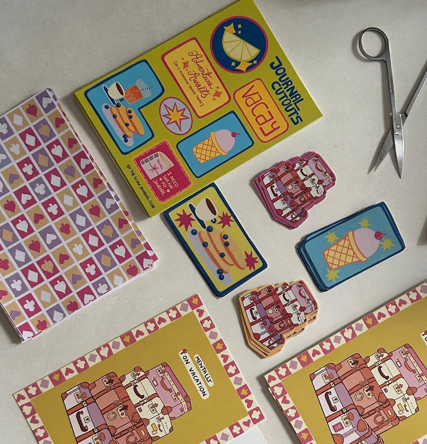 Colorful journalling supplies and stickers on a white surface with scissors. 