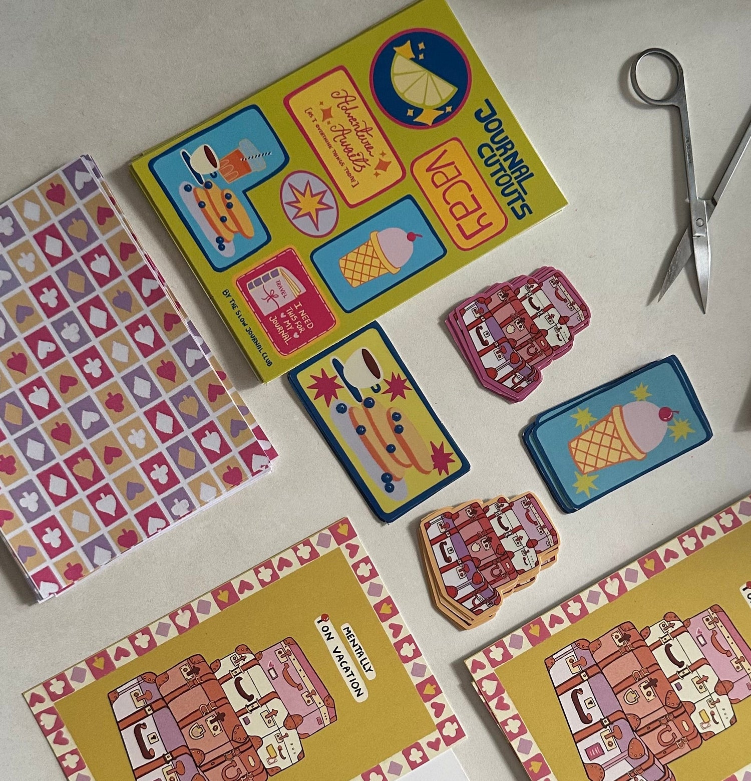 Colorful journalling supplies and stickers on a white surface with scissors. 