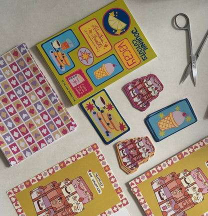 Colorful journalling supplies and stickers on a white surface with scissors. 